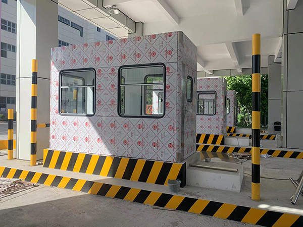 收費崗?fù)?></div>尺寸規(guī)劃<br>需根據(jù)收費人員數(shù)量、設(shè)備擺放需求確定內(nèi)部空間，確保操作便捷（如單人崗?fù)魧挷恍∮?1.2m）。<br>窗口高度通常為 0.8~1.2m，便于與駕駛員交互。<br>結(jié)構(gòu)設(shè)計<br>抗風(fēng)抗震：沿海或多臺風(fēng)地區(qū)需加固結(jié)構(gòu)，采用鋼結(jié)構(gòu)框架 + 螺栓連接，抗風(fēng)等級可達 10 級以上。<br>防水密封：屋頂采用坡度設(shè)計（≥5°），接縫處使用防水膠條或密封膠，避免雨水滲漏。<br>隔音降噪：墻體填充隔音材料（如巖棉、聚氨酯泡沫），減少外部噪音干擾。<br>外觀與標(biāo)識<br>顏色通常與企業(yè) VI 或場景風(fēng)格統(tǒng)一（如高速公路常用藍色、灰色），表面可做噴漆或貼膜處理。<br>醒目位置設(shè)置收費標(biāo)準(zhǔn)公示牌、服務(wù)熱線標(biāo)識等，提升用戶體驗。<br>電氣與智能化<br>預(yù)留電源接口（如 220V 插座、配電箱），滿足收費設(shè)備、空調(diào)等用電需求。<br>集成智能化系統(tǒng)時，需提前規(guī)劃線路走向，避免信號干擾（如強弱電分離）。<br><br>
	</div>

    <div style=