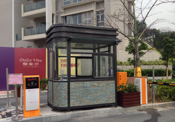 鋼結(jié)構(gòu)崗?fù)?></div>一、強(qiáng)化防銹防腐處理，阻斷銹蝕源頭<br>鋼結(jié)構(gòu)的主要老化原因是金屬銹蝕，需從 “防護(hù)層維護(hù)” 和 “銹蝕處理” 兩方面入手：<br>定期檢查并修復(fù)表面涂層<br>崗?fù)ぶ黧w鋼結(jié)構(gòu)（框架、面板）通常會做噴漆、鍍鋅或氟碳涂層處理，這些涂層是阻斷空氣、水分與鋼材接觸的關(guān)鍵。需每月檢查涂層是否有脫落、開裂、劃痕：<br>輕微劃痕或小面積脫落：用砂紙打磨干凈后，補(bǔ)涂同類型防銹漆（如環(huán)氧底漆 + 面漆），確保涂層完整；<br>大面積涂層損壞：徹底清除舊涂層，重新進(jìn)行除銹（噴砂或酸洗）和噴漆處理，避免銹蝕擴(kuò)散。<br>重點(diǎn)檢查焊接點(diǎn)、邊角等易積水部位，這些區(qū)域涂層易因應(yīng)力或潮濕提前損壞。<br>針對性處理局部銹蝕<br>發(fā)現(xiàn)銹跡后及時處理：用鋼絲刷或砂紙打磨至露出金屬本色，去除銹渣后，先涂防銹底漆，再補(bǔ)面漆；<br>若銹蝕已深入鋼材（出現(xiàn)坑點(diǎn)或變?。?，需評估結(jié)構(gòu)安全性，必要時切割更換銹蝕部件（如立柱、橫梁），并重新焊接、做防腐處理。<br>二、維護(hù)結(jié)構(gòu)穩(wěn)定性，避免力學(xué)損傷<br>鋼結(jié)構(gòu)崗?fù)さ目蚣?、連接件等承受整體荷載，需定期檢查并加固：<br>緊固連接部件<br>崗?fù)さ穆萁z、螺栓、鉚釘?shù)冗B接件，長期受振動（如車輛經(jīng)過、人員活動）或溫差影響可能松動：<br>每季度檢查一次所有連接件，用扳手緊固松動的螺絲，對滑絲、生銹的螺栓及時更換（優(yōu)先選用不銹鋼材質(zhì)，避免二次銹蝕）；<br>焊接部位若出現(xiàn)焊縫開裂，需清理后重新補(bǔ)焊，并對焊縫做防銹處理（涂防銹漆）。<br>防止結(jié)構(gòu)變形<br>避免崗?fù)こ惺艹d（如頂部堆放重物、側(cè)面受撞擊），若因外力導(dǎo)致框架變形（如門窗無法閉合、面板凹陷），需及時用千斤頂、扳手等工具矯正，嚴(yán)重變形時需更換受損構(gòu)件；<br>安裝在崗?fù)さ撞康某兄丶芑虻啬_螺栓，需檢查是否與地面固定牢固，防止因地基沉降導(dǎo)致崗?fù)A斜，進(jìn)而引發(fā)結(jié)構(gòu)應(yīng)力集中。<br>三、優(yōu)化使用環(huán)境，減少外部侵蝕<br>環(huán)境因素（如濕度、鹽分、污染物）是加速鋼結(jié)構(gòu)老化的重要誘因，需針對性防護(hù)：<br>控制內(nèi)部濕度與排水<br>崗?fù)?nèi)部若因漏水、冷凝水積聚導(dǎo)致潮濕，會加速鋼材銹蝕：<br>檢查門窗密封條是否老化，及時更換硅膠條，防止雨水滲入；<br>底部加裝排水孔（配濾網(wǎng)防堵塞），避免積水浸泡底部鋼結(jié)構(gòu)；<br>潮濕地區(qū)可在內(nèi)部放置除濕袋或小型除濕機(jī)，保持相對濕度低于 60%。<br>應(yīng)對特殊環(huán)境的額外防護(hù)<br>沿海 / 高鹽霧地區(qū)：崗?fù)け砻婵深~外噴涂耐鹽霧涂料（如聚脲涂層），每 2-3 年重新噴涂一次；地腳螺栓等金屬部件可涂覆防銹油脂，減少鹽分侵蝕。<br>工業(yè)區(qū) / 粉塵多的場所：每周清潔崗?fù)け砻?，用中性清潔劑去除油污、粉塵（避免用強(qiáng)酸強(qiáng)堿，防止破壞涂層），減少污染物對涂層的腐蝕。<br>戶外高溫 / 強(qiáng)紫外線環(huán)境：定期檢查涂層是否因暴曬出現(xiàn)粉化、褪色，及時補(bǔ)涂抗紫外線面漆，延長涂層壽命。<br>四、日常使用與細(xì)節(jié)保養(yǎng)<br>規(guī)范使用行為<br>避免用硬物（如鐵鍬、鋼管）撞擊崗?fù)た蚣芑蛎姘?，防止涂層破損和結(jié)構(gòu)變形；<br>門窗開合時輕推輕拉，定期給合頁、鎖芯添加潤滑劑（如石墨粉、硅基潤滑脂），避免因卡頓用力拉扯導(dǎo)致連接件損壞。<br>定期全面保養(yǎng)<br>每半年進(jìn)行一次 “全身體檢”：檢查鋼結(jié)構(gòu)整體平整度、涂層完整性、連接件狀態(tài)、內(nèi)部電路（避免線路老化短路引發(fā)高溫?fù)p壞鋼材）等；<br>冬季來臨前，清理崗?fù)ろ敳糠e雪（尤其厚重積雪可能壓垮頂部結(jié)構(gòu)），北方地區(qū)可在底部加裝保溫層，減少溫差導(dǎo)致的鋼材熱脹冷縮應(yīng)力。<br><div style=